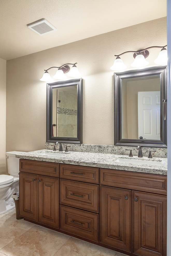 Mid-sized transitional master beige tile and porcelain tile porcelain tile and beige floor alcove shower photo in Phoenix with shaker cabinets, dark wood cabinets, a two-piece toilet, beige walls, an undermount sink, granite countertops and a hinged shower door