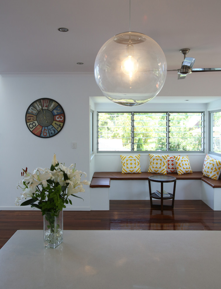 Tropical galley kitchen in Brisbane with flat-panel cabinets, white cabinets, quartz benchtops, medium hardwood floors, with island and white benchtop.