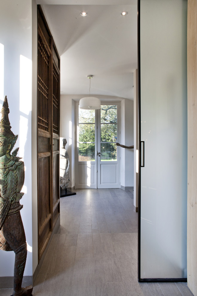 This is an example of an eclectic hallway in Paris with white walls, laminate floors and beige floor.