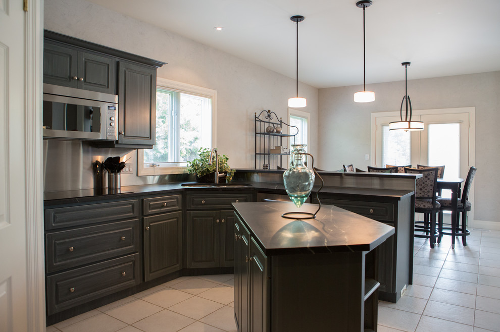 Example of a mid-sized transitional u-shaped ceramic tile enclosed kitchen design in Toronto with an undermount sink, raised-panel cabinets, blue cabinets, soapstone countertops, metallic backsplash and an island