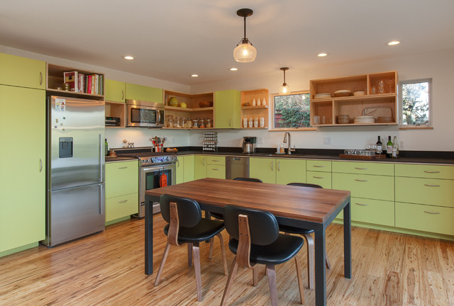 Mid-sized modern l-shaped eat-in kitchen in Seattle with an undermount sink, flat-panel cabinets, green cabinets, solid surface benchtops, black splashback, stainless steel appliances, medium hardwood floors and no island.