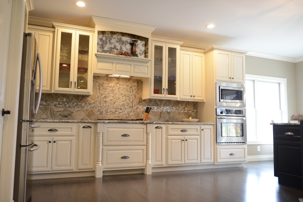 Eat-in kitchen - huge transitional l-shaped medium tone wood floor eat-in kitchen idea in Chicago with a farmhouse sink, raised-panel cabinets, white cabinets, granite countertops, beige backsplash, stone tile backsplash, stainless steel appliances and an island