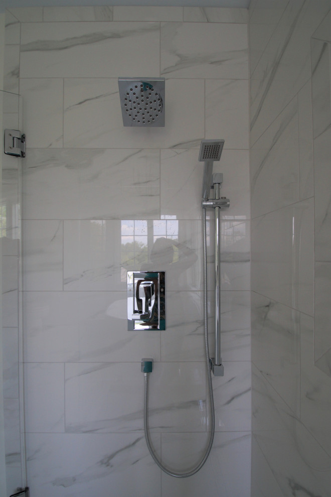 This is an example of a medium sized contemporary ensuite bathroom in Other with shaker cabinets, white cabinets, a freestanding bath, a corner shower, a two-piece toilet, white tiles, porcelain tiles, white walls, porcelain flooring, a submerged sink, marble worktops, white floors, a sliding door, white worktops, a wall niche, double sinks, a freestanding vanity unit and a vaulted ceiling.