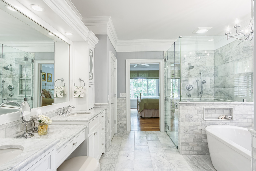 Inspiration for a traditional master bathroom in Columbus with recessed-panel cabinets, white cabinets, a freestanding tub, a corner shower, gray tile, grey walls, an undermount sink, grey floor and a hinged shower door.