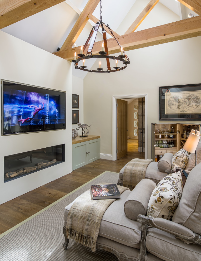 Photo of a mid-sized country family room in Gloucestershire with beige walls, medium hardwood floors, a ribbon fireplace, a wall-mounted tv, brown floor and exposed beam.