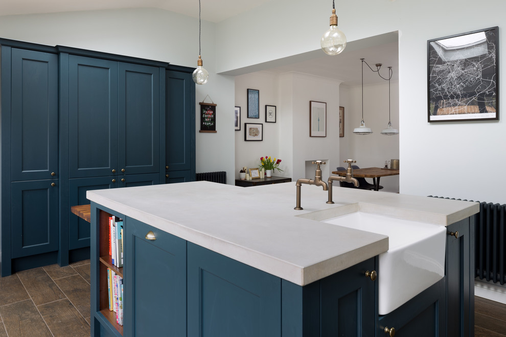Inspiration for a mid-sized transitional eat-in kitchen in Other with a farmhouse sink, shaker cabinets, blue cabinets, concrete benchtops, black appliances, porcelain floors, with island and brown floor.