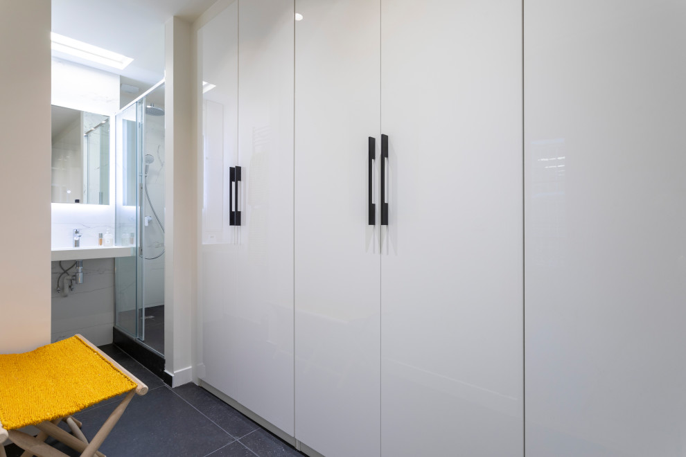 Idée de décoration pour un petit dressing room design neutre avec un placard à porte plane, des portes de placard blanches, un sol en ardoise et un sol gris.