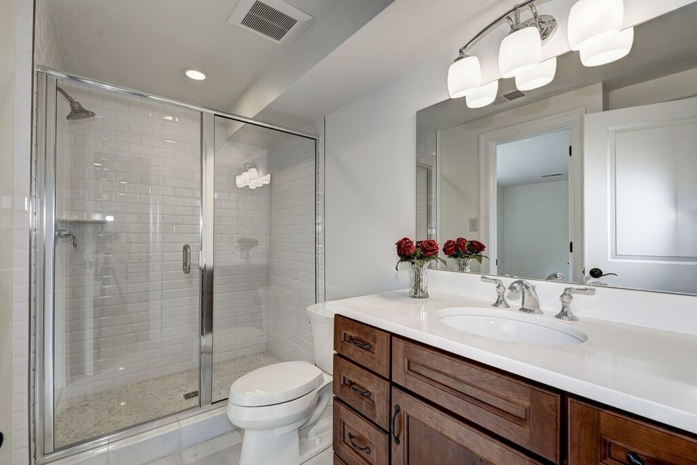 Example of a mid-sized transitional 3/4 white tile and subway tile ceramic tile alcove shower design in DC Metro with beaded inset cabinets, medium tone wood cabinets, a one-piece toilet, white walls, a drop-in sink and granite countertops