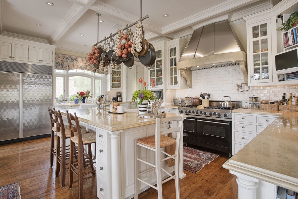 Large traditional u-shaped eat-in kitchen in San Francisco with stainless steel appliances, a farmhouse sink, beaded inset cabinets, white cabinets, limestone benchtops, white splashback, ceramic splashback, medium hardwood floors and with island.