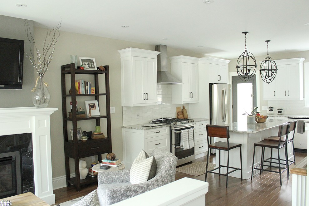 Small transitional l-shaped open plan kitchen in Toronto with an undermount sink, recessed-panel cabinets, white cabinets, solid surface benchtops, white splashback, subway tile splashback, stainless steel appliances and medium hardwood floors.