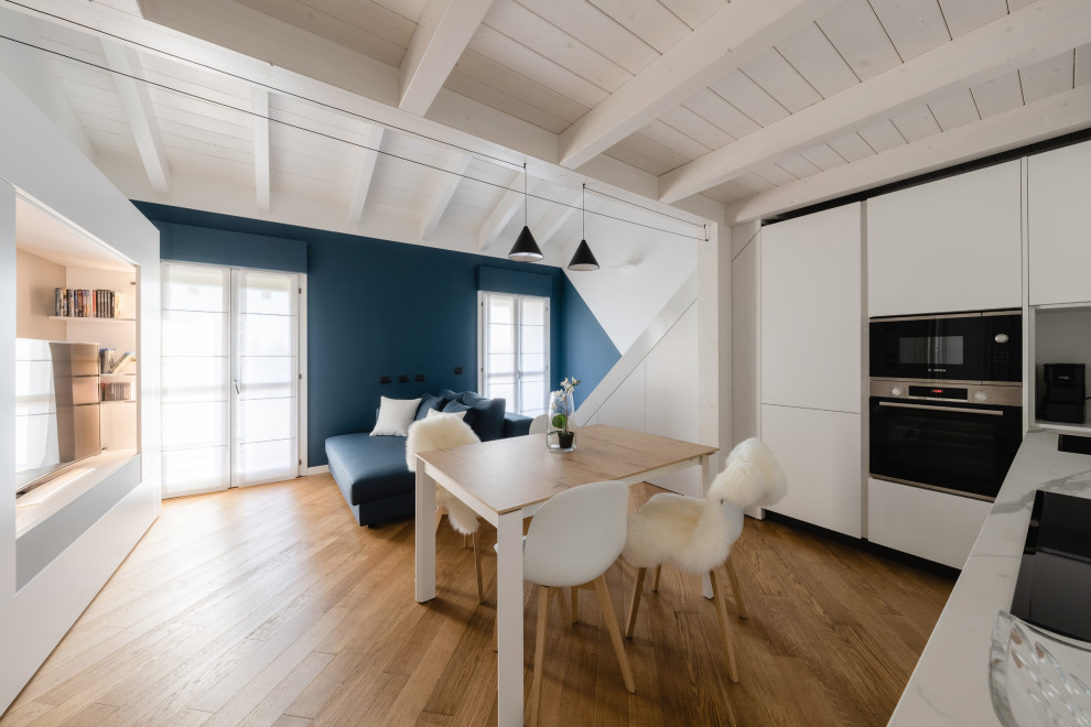Foto på ett litet minimalistiskt allrum med öppen planlösning, med ett musikrum, flerfärgade väggar, ljust trägolv, en inbyggd mediavägg och beiget golv