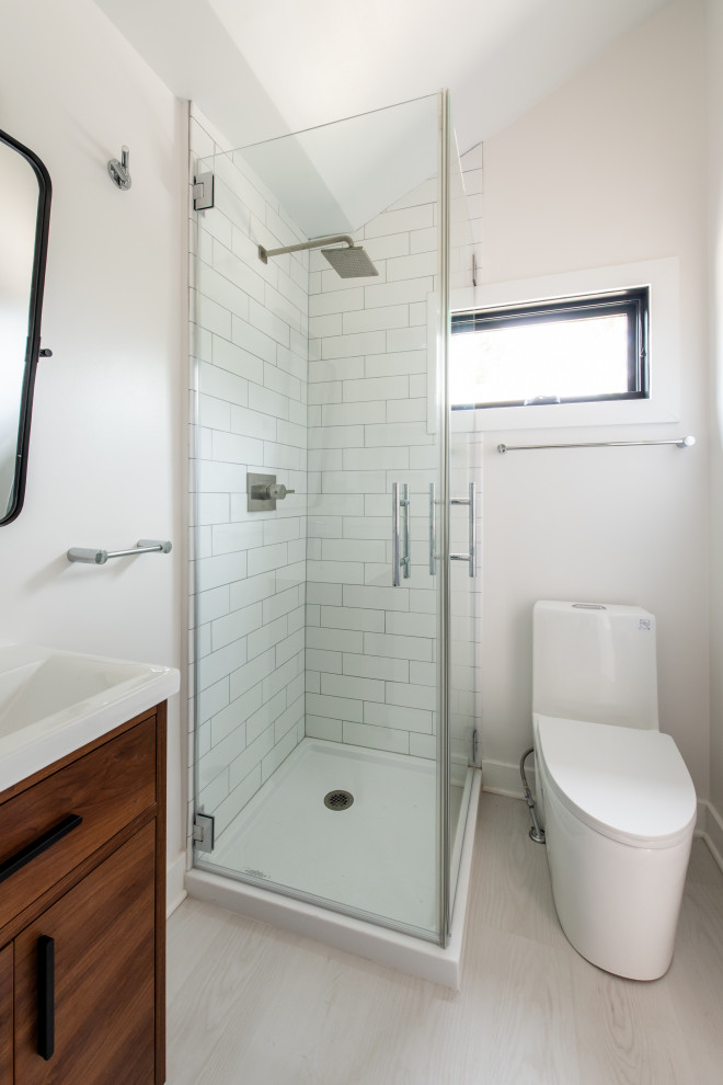 Inspiration for a small contemporary shower room bathroom in DC Metro with medium wood cabinets, a corner shower, a one-piece toilet, white tiles, metro tiles, white walls, lino flooring, a console sink, grey floors, a hinged door, a laundry area, a single sink, a built in vanity unit and flat-panel cabinets.