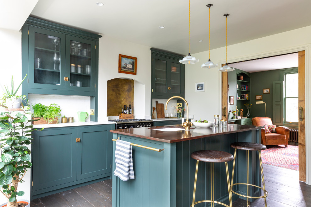 Photo of a mid-sized transitional single-wall eat-in kitchen in London with shaker cabinets, green cabinets, medium hardwood floors, with island, brown floor, a farmhouse sink, quartzite benchtops, metallic splashback, marble splashback, black appliances and white benchtop.