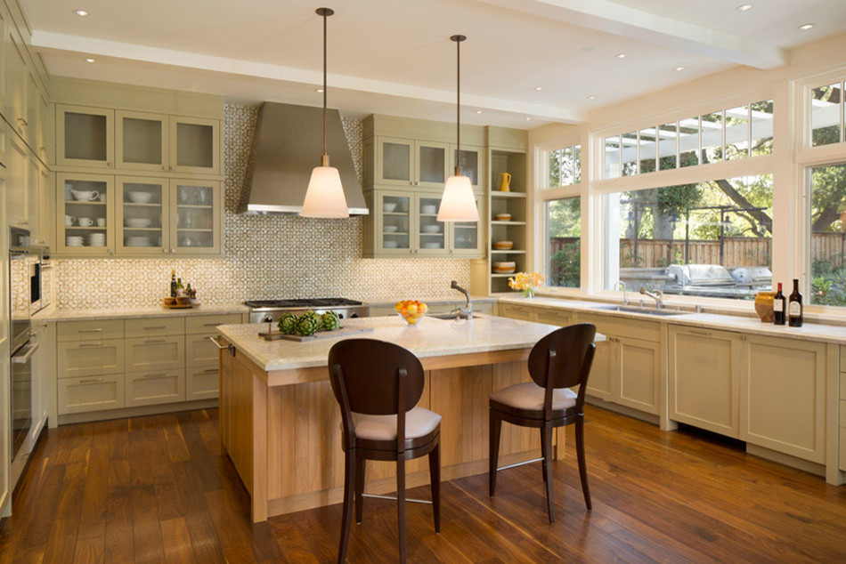 Photo of a mid-sized contemporary u-shaped eat-in kitchen in San Francisco with glass-front cabinets, stainless steel appliances, medium hardwood floors, with island and beige cabinets.