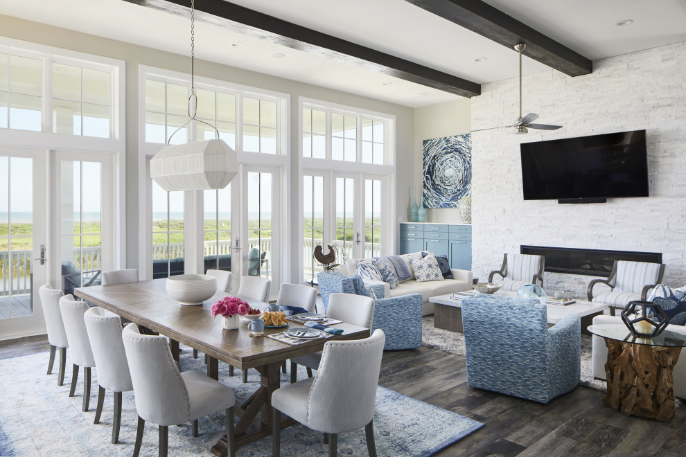 Expansive beach style enclosed family room in Other with grey walls, vinyl floors, a ribbon fireplace, a wall-mounted tv, brown floor and exposed beam.