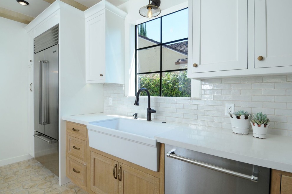 Photo of a mid-sized mediterranean galley separate kitchen in Los Angeles with a farmhouse sink, shaker cabinets, beige cabinets, quartz benchtops, blue splashback, mosaic tile splashback, stainless steel appliances, brick floors, no island and beige floor.