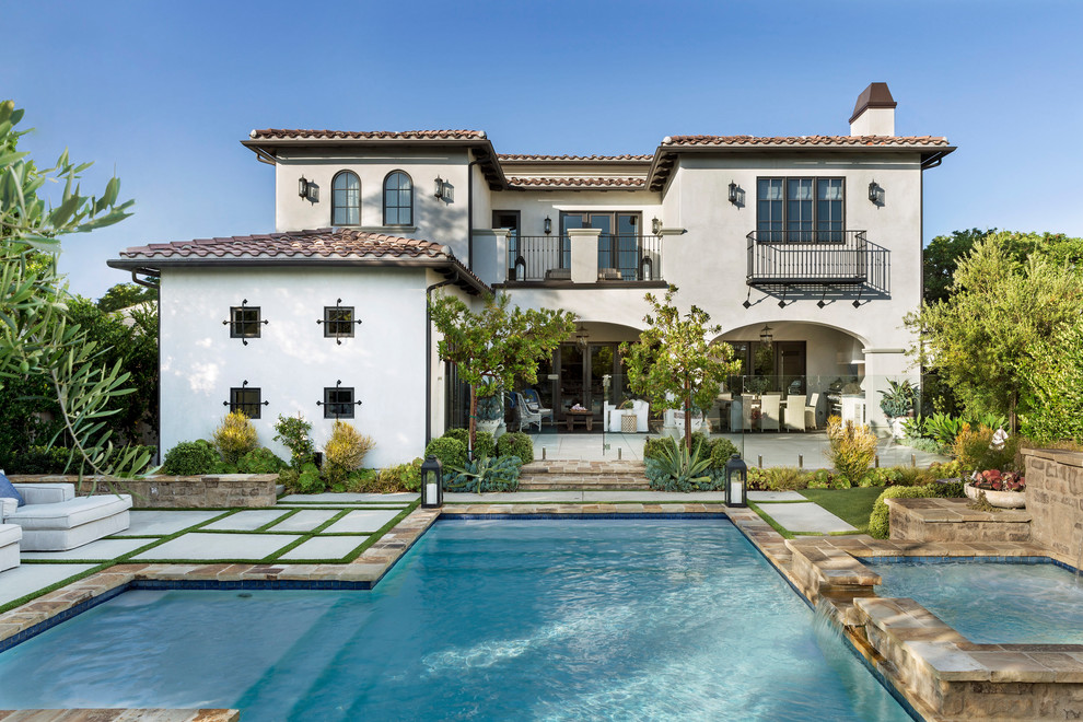 Photo of a mediterranean two-storey stucco white house exterior in Other with a hip roof and a tile roof.