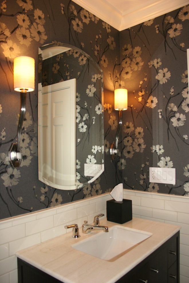 Photo of a small transitional powder room in New York with furniture-like cabinets, dark wood cabinets, a two-piece toilet, beige tile, subway tile, an undermount sink, onyx benchtops, porcelain floors, multi-coloured walls, a freestanding vanity, wallpaper, white floor and beige benchtops.