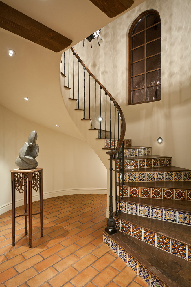 Photo of a mediterranean wood curved staircase in Phoenix with tile risers and metal railing.