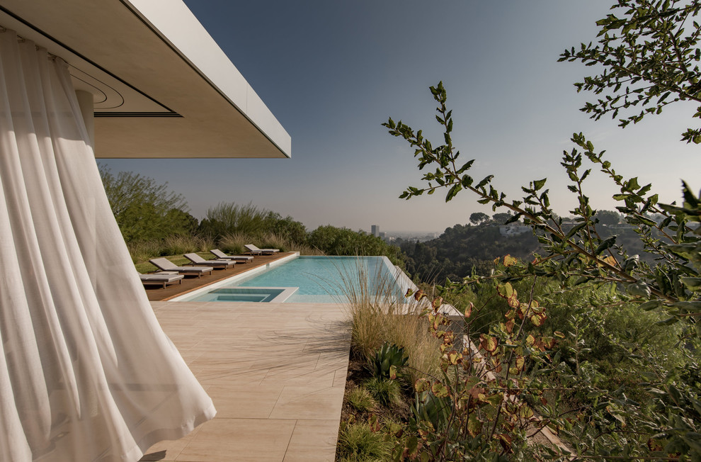 This is an example of a midcentury rectangular infinity pool in Los Angeles with a hot tub.