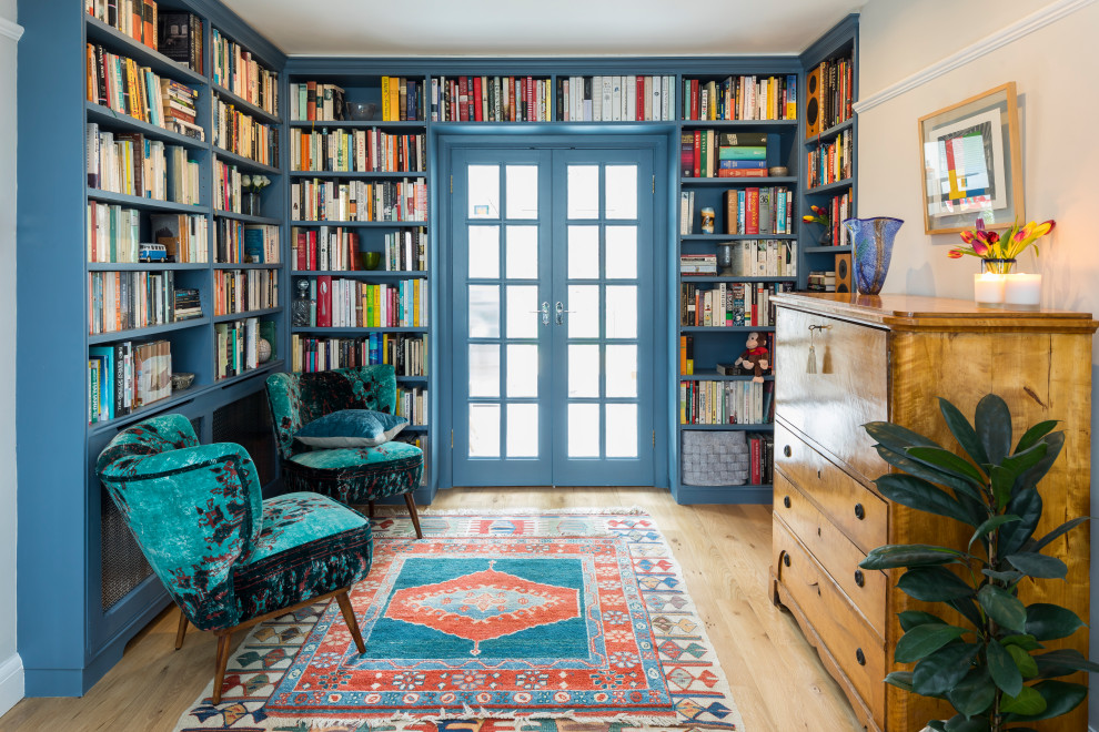 Photo of an eclectic family room in London with a library, beige walls, light hardwood floors and beige floor.