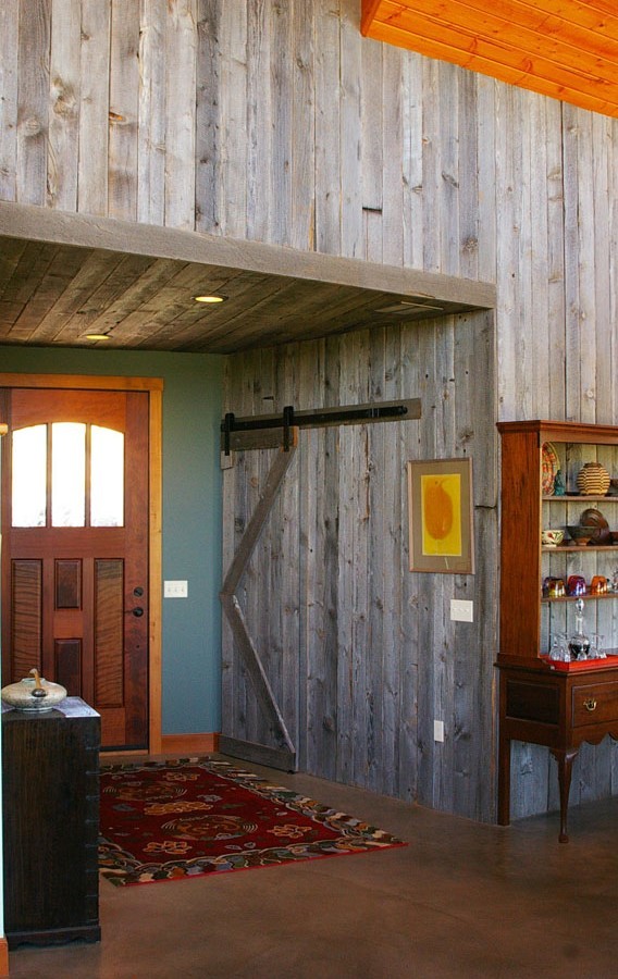 Mid-sized country front door in Seattle with grey walls, concrete floors, a single front door, a medium wood front door and brown floor.