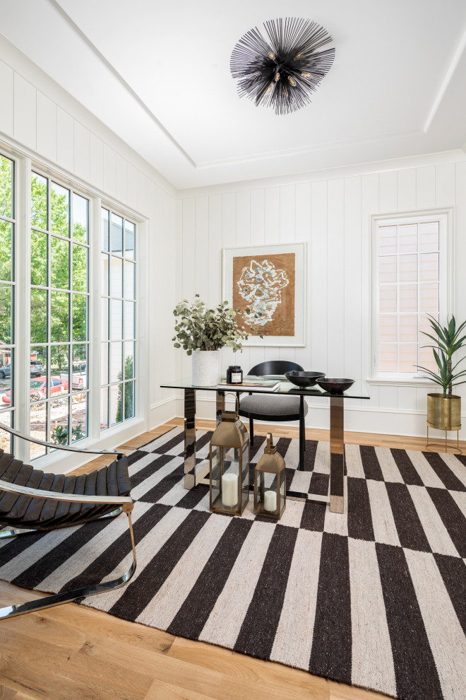 Immagine di uno studio minimalista con pareti bianche, parquet chiaro, scrivania autoportante e pareti in perlinato