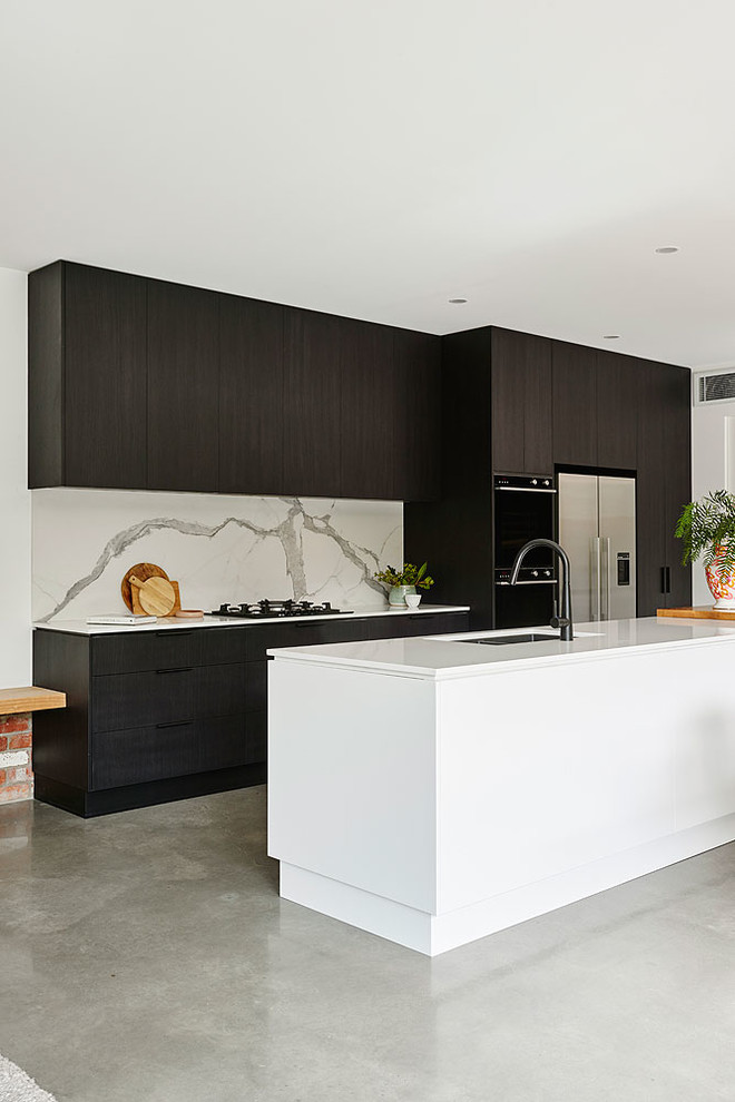 Design ideas for a contemporary galley open plan kitchen in Geelong with an undermount sink, quartz benchtops, white splashback, marble splashback, black appliances, concrete floors, with island, grey floor and white benchtop.