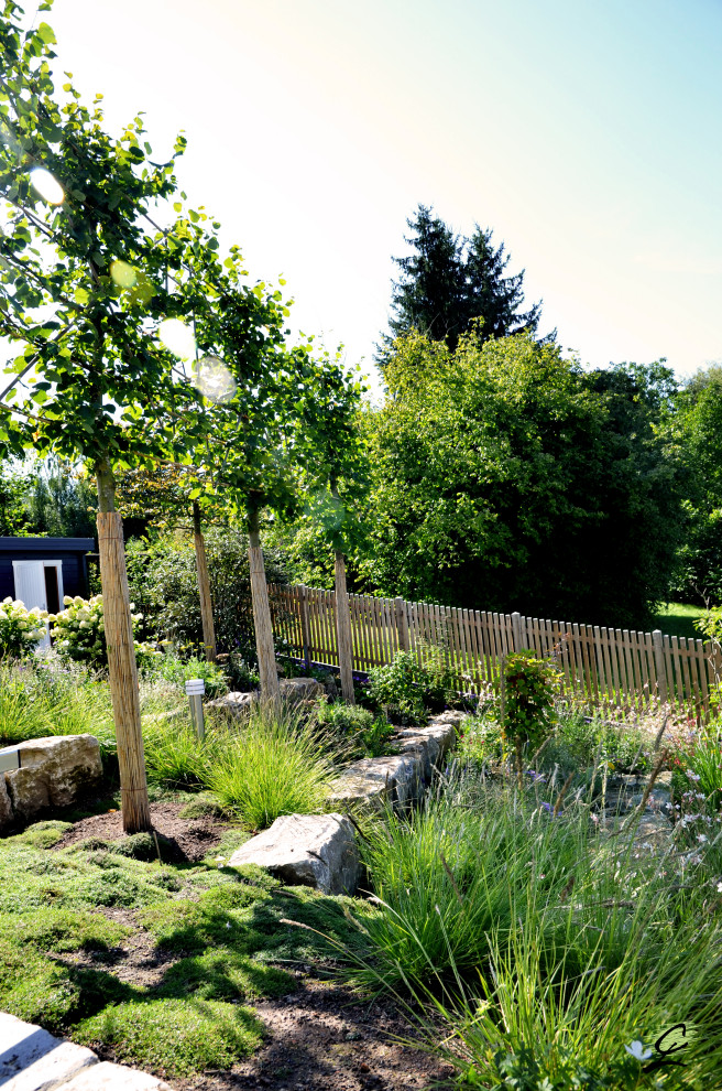 Foto di un grande giardino country esposto in pieno sole davanti casa in estate con pavimentazioni in pietra naturale