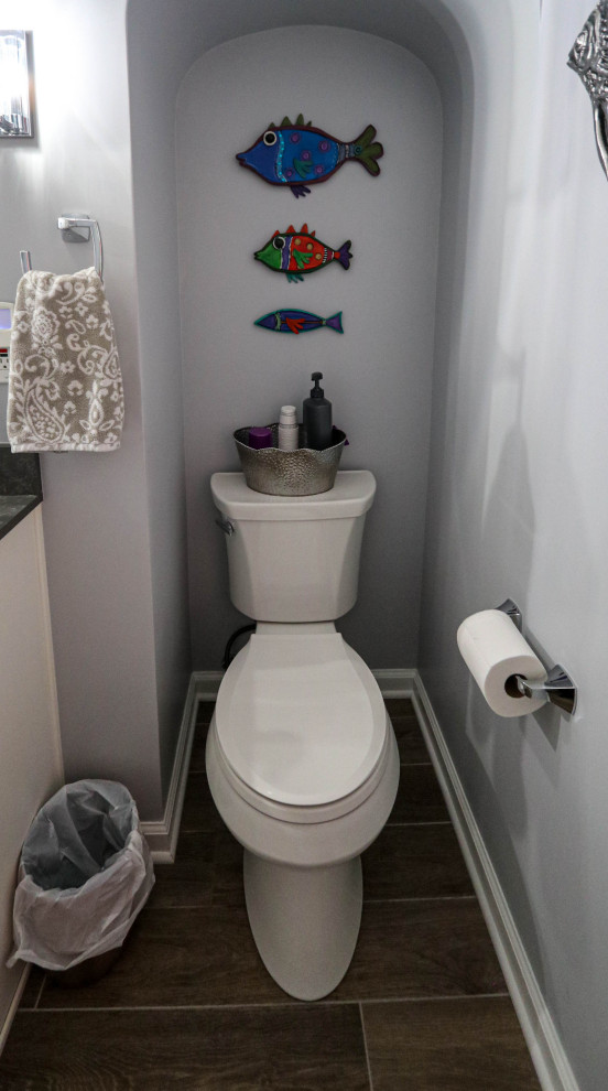 Inspiration för små klassiska grått toaletter, med luckor med upphöjd panel, vita skåp, en toalettstol med separat cisternkåpa, grå kakel, cementgolv, ett undermonterad handfat, bänkskiva i kvarts och brunt golv