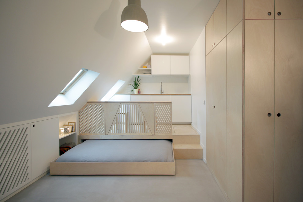 Small contemporary loft-style bedroom in Paris with white walls, concrete floors and no fireplace.