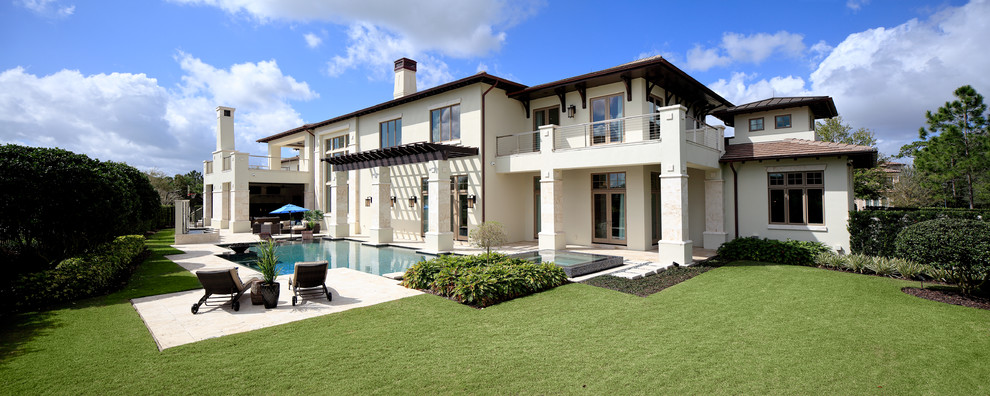 This is an example of an expansive mediterranean two-storey stucco beige house exterior in Orlando with a hip roof and a tile roof.