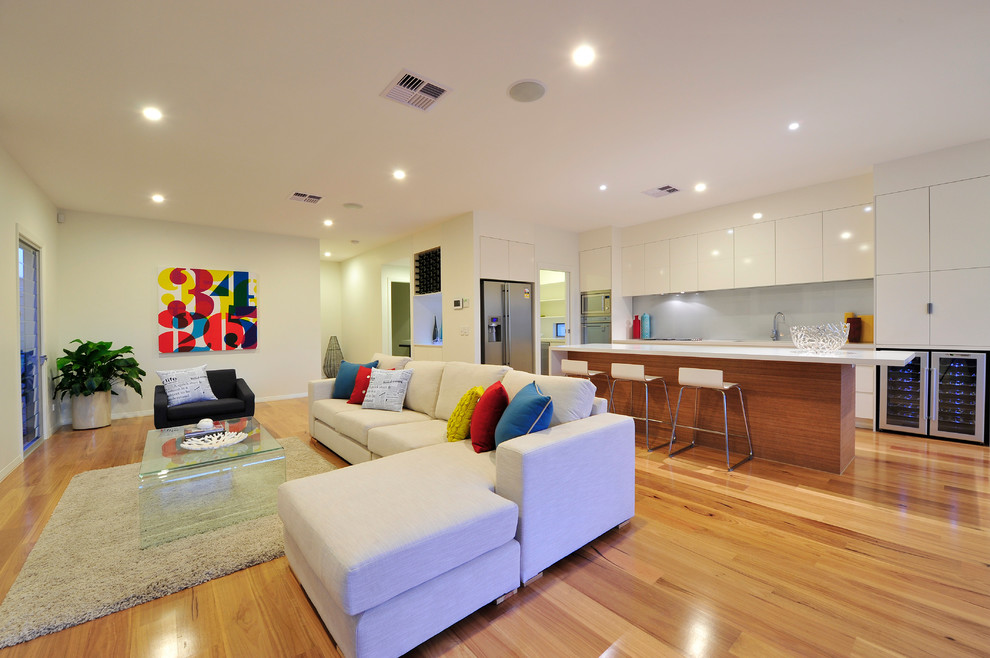 This is an example of a mid-sized contemporary open concept living room in Brisbane with white walls, medium hardwood floors, a standard fireplace, a metal fireplace surround and a built-in media wall.