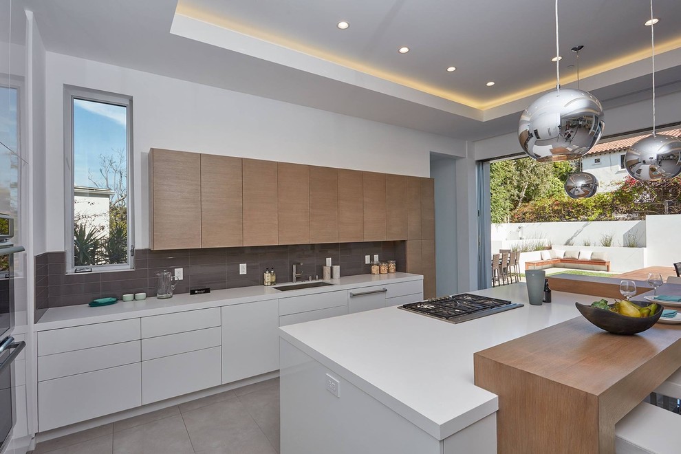 Design ideas for a large contemporary u-shaped eat-in kitchen in Orange County with an undermount sink, flat-panel cabinets, white cabinets, quartz benchtops, beige splashback, porcelain splashback, panelled appliances, concrete floors, with island, grey floor and white benchtop.