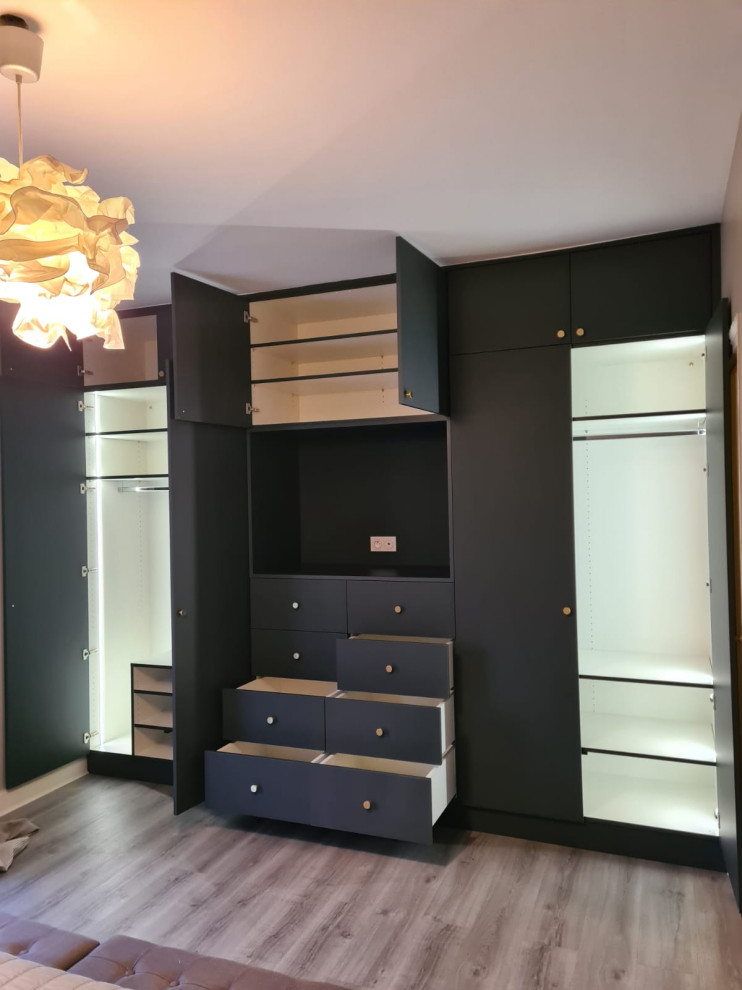 This is an example of a large modern gender-neutral walk-in wardrobe in Other with beaded inset cabinets, grey cabinets, laminate floors and brown floor.