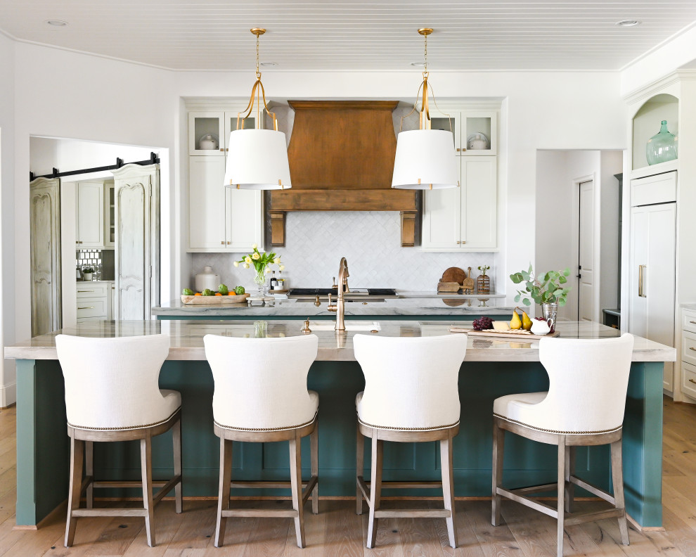 Bild på ett mellanstort grå grått kök, med en rustik diskho, luckor med infälld panel, vita skåp, granitbänkskiva, grått stänkskydd, stänkskydd i keramik, integrerade vitvaror, mellanmörkt trägolv och flera köksöar