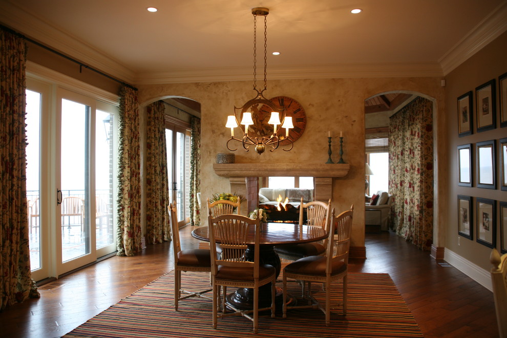 Photo of a traditional dining room in Cleveland with brown walls, dark hardwood floors and a two-sided fireplace.