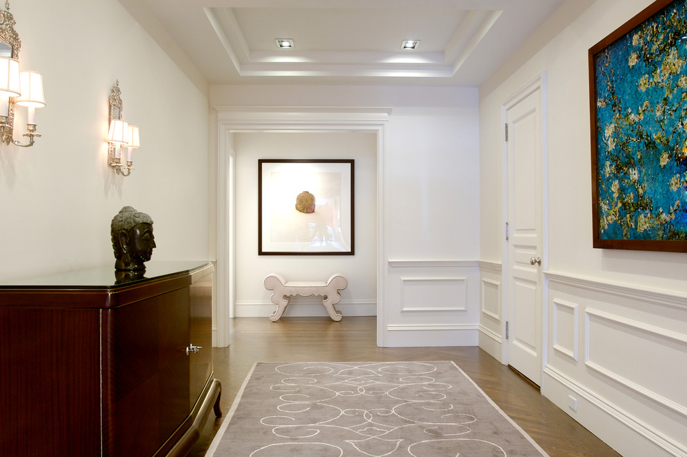 Photo of a large transitional hallway in New York with white walls and medium hardwood floors.