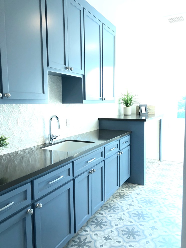 Large beach style single-wall dedicated laundry room in San Francisco with an undermount sink, shaker cabinets, blue cabinets, quartzite benchtops, white walls, ceramic floors, a side-by-side washer and dryer, blue floor and grey benchtop.