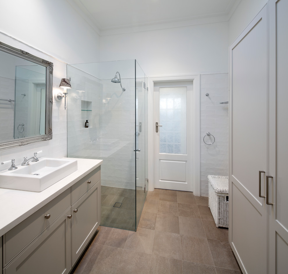Photo of a mid-sized transitional bathroom in Sydney with shaker cabinets, blue cabinets, a drop-in tub, an open shower, a two-piece toilet, ceramic tile, light hardwood floors, a drop-in sink, engineered quartz benchtops and a hinged shower door.
