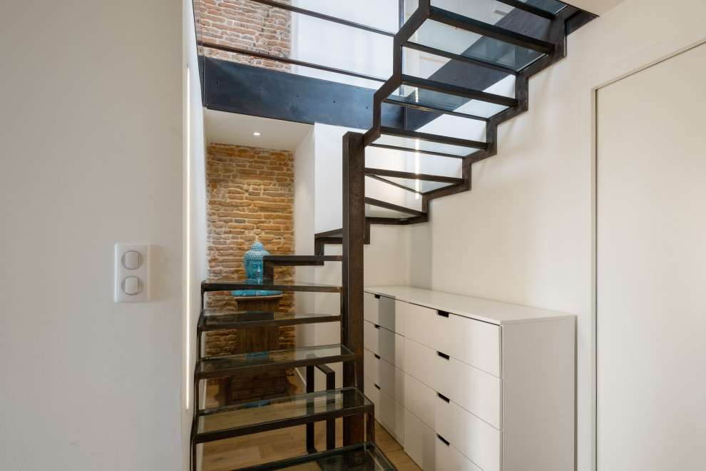 Exemple d'un escalier sans contremarche courbe industriel de taille moyenne avec des marches en verre, un garde-corps en métal et un mur en parement de brique.