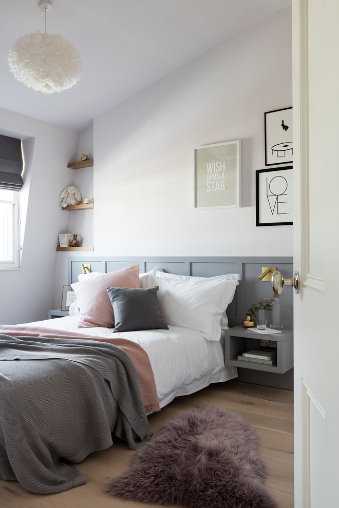 Photo of a mid-sized transitional gender-neutral kids' room in London with white walls, light hardwood floors and beige floor.