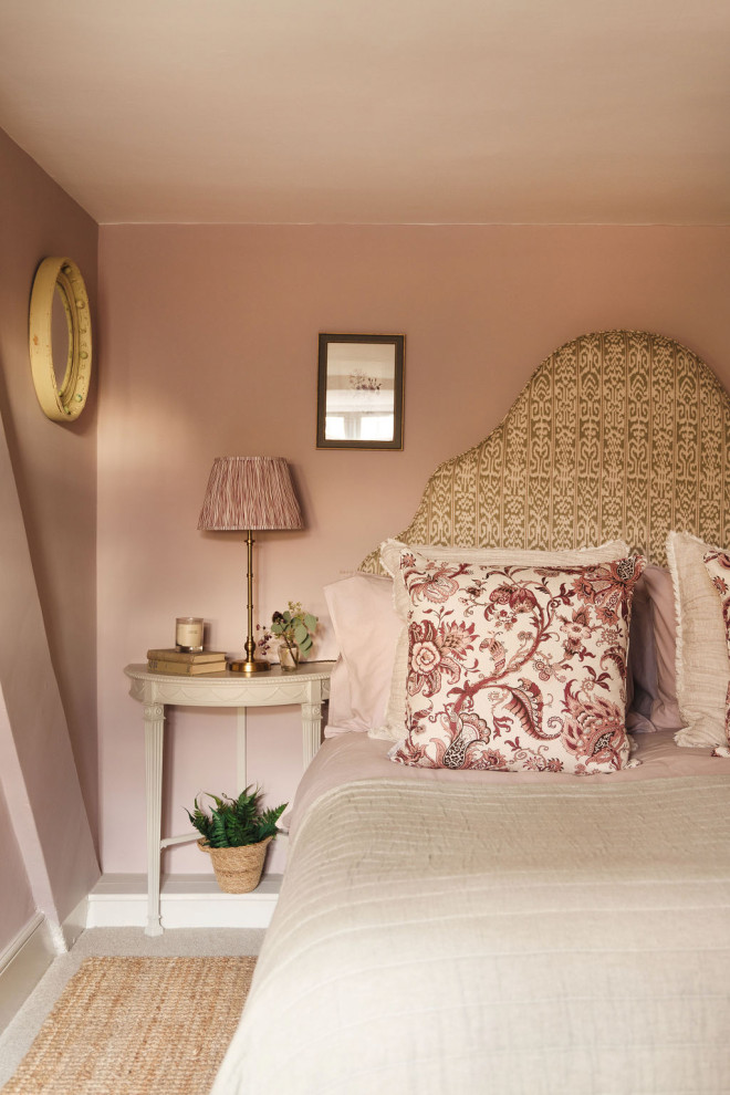 Inspiration for a mid-sized farmhouse guest carpeted and beige floor bedroom remodel in Gloucestershire with pink walls