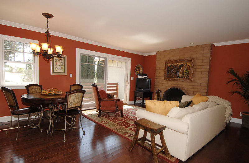This is an example of a mid-sized traditional open concept family room in San Francisco with orange walls, dark hardwood floors, a standard fireplace, a brick fireplace surround, a freestanding tv and brown floor.