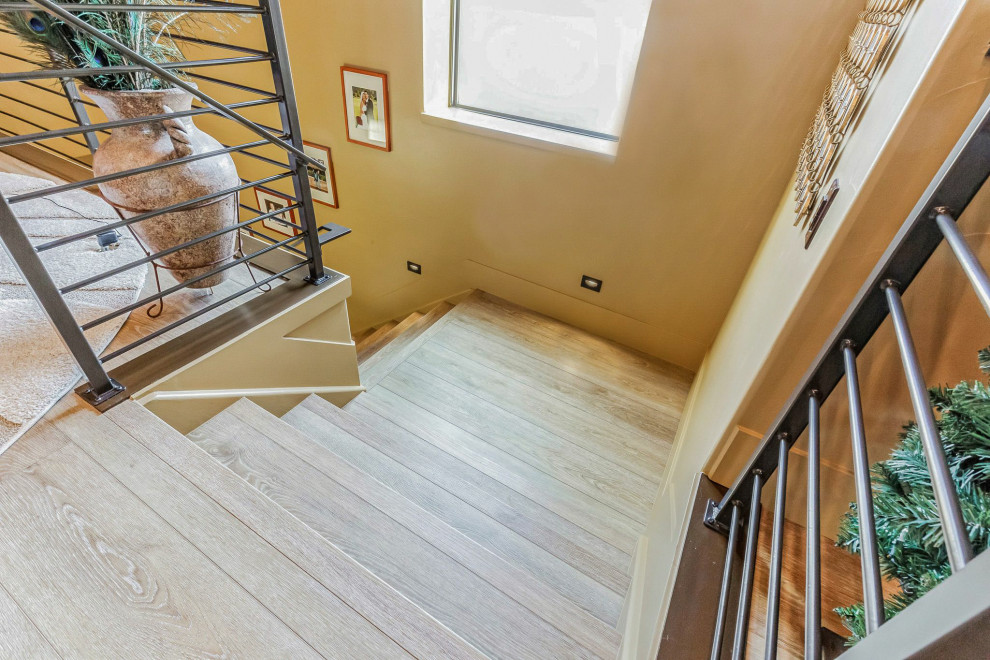 Пример оригинального дизайна: угловая деревянная лестница среднего размера в стиле фьюжн с деревянными ступенями и металлическими перилами
