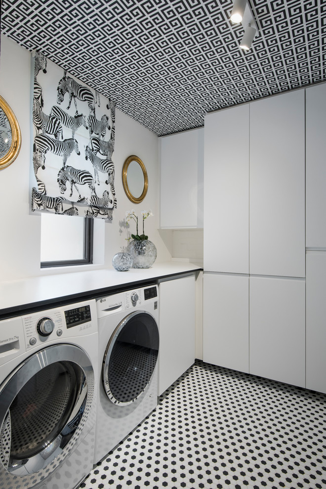 Mid-sized contemporary single-wall dedicated laundry room in London with white cabinets, white walls, a side-by-side washer and dryer, flat-panel cabinets and multi-coloured floor.