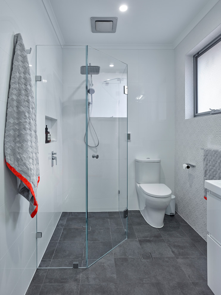Inspiration for a small contemporary 3/4 bathroom in Other with white cabinets, an alcove shower, a one-piece toilet, white tile, porcelain tile, white walls, ceramic floors and an integrated sink.