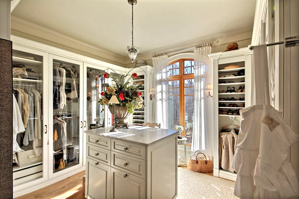 Design ideas for a traditional dressing room in Atlanta with white cabinets and light hardwood floors.