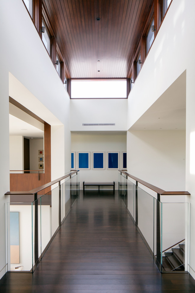 This is an example of a large contemporary hallway in Los Angeles with white walls and dark hardwood floors.