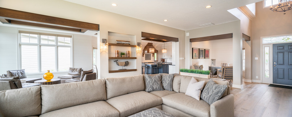 Mid-sized transitional open concept family room in Indianapolis with beige walls, light hardwood floors, a standard fireplace, a stone fireplace surround, a wall-mounted tv and beige floor.
